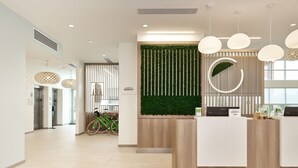 Ein Empfangsbereich mit einem Holzbüro, einer vertikalen grünen Wand und einem Fahrrad im Hintergrund.