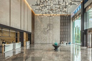 Un vestíbulo espacioso con una recepción, iluminación moderna y un ventanal que ofrece vistas al exterior.