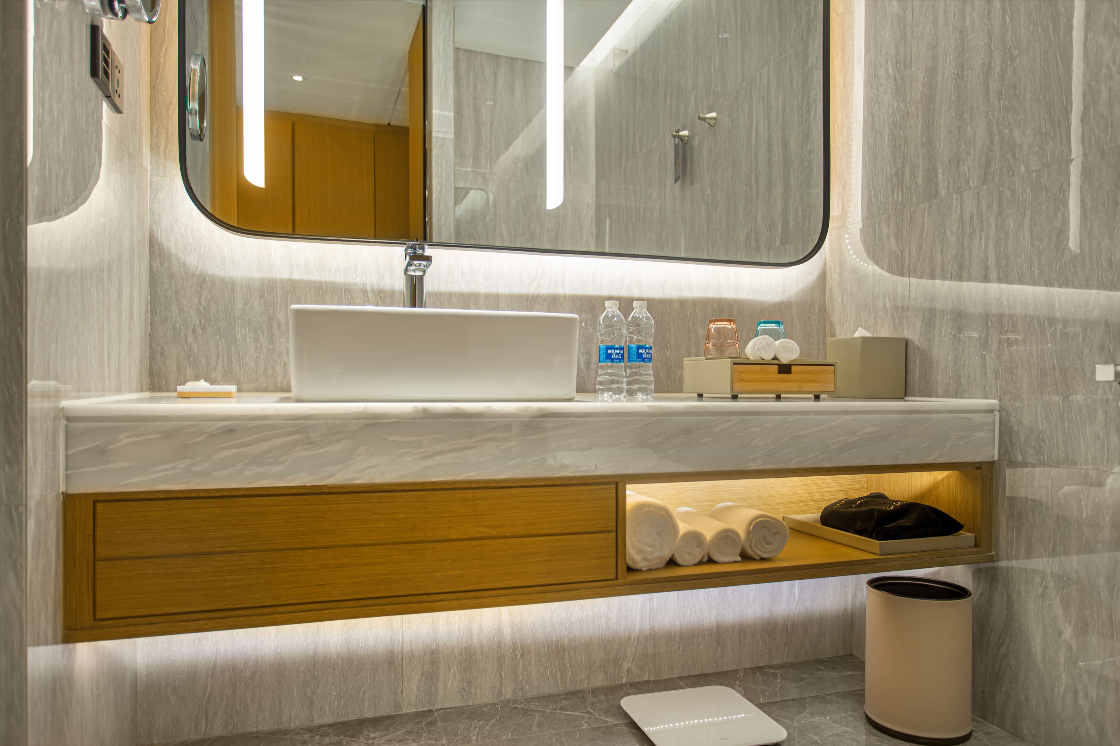 A modern bathroom with a marble sink, wooden vanity, and a mirror.