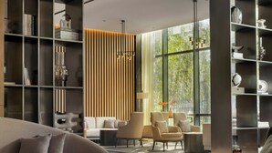 Ein modernes Wohnzimmer mit einer Couch, Sesseln, einem Bücherregal und einem großen Fenster.