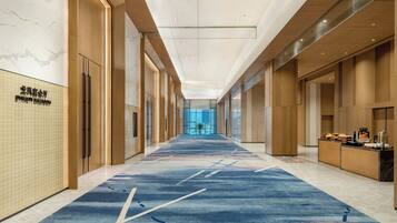 A hotel corridor with a blue carpet, wooden paneling, and a reception desk.