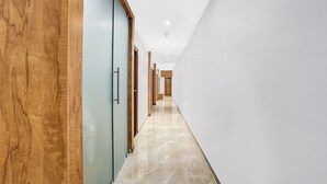 A modern hallway with wooden paneling on one side and a marble floor. - Itsy Hotels Heraa International (Mumbai)