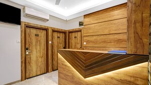 A hotel reception area with wooden paneling, numbered doors, and a check-in/out sign. - Itsy Hotels Heraa International (Mumbai)