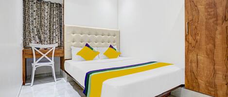 A bedroom with a bed, a desk, and a chair.