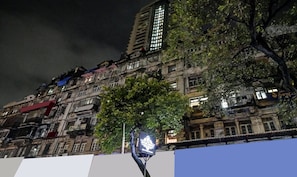Un edificio histórico de varios pisos, con elementos arquitectónicos tradicionales y un árbol en primer plano.