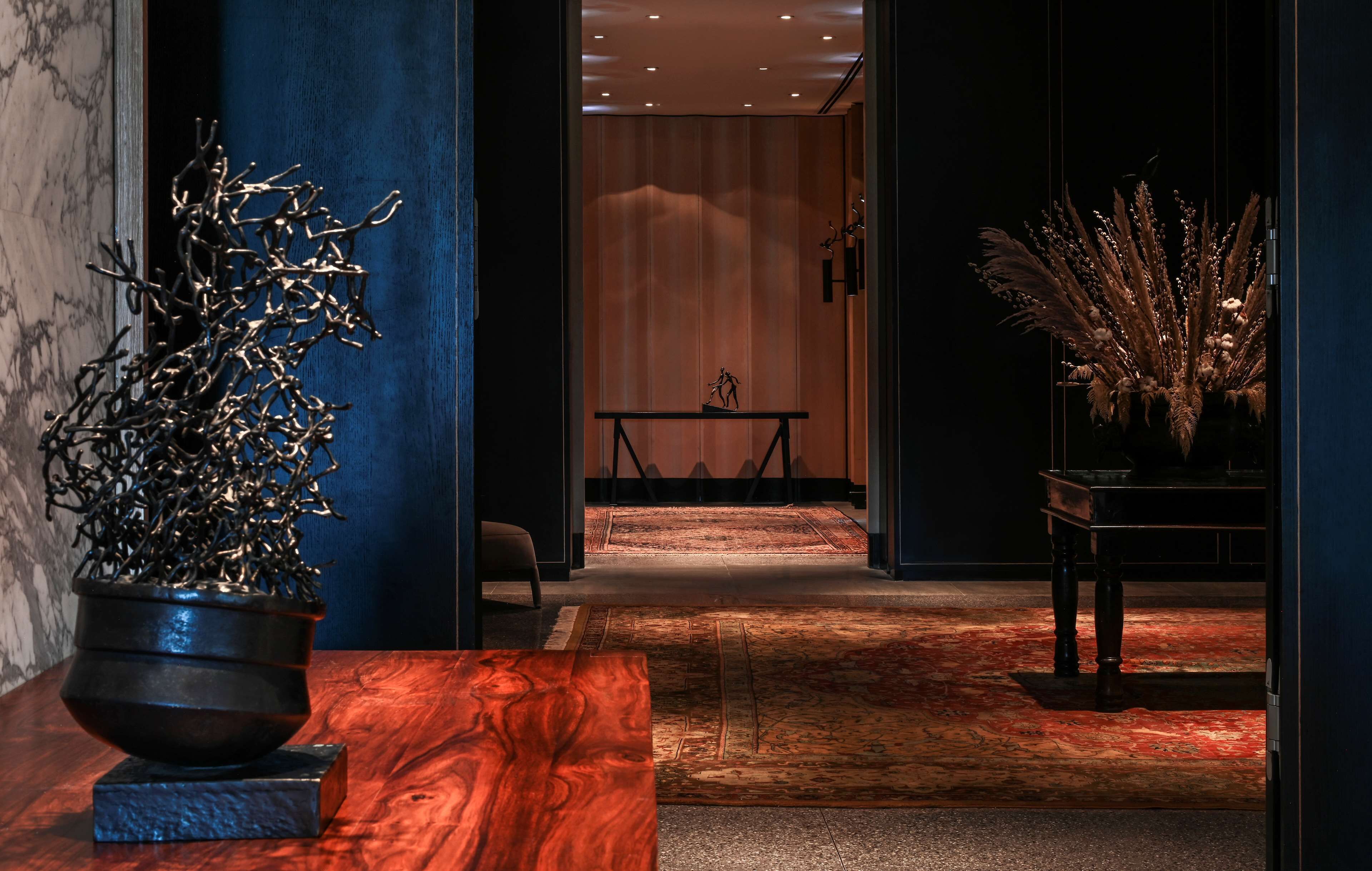 A hallway with a wooden table, a potted plant, and a decorative arrangement.