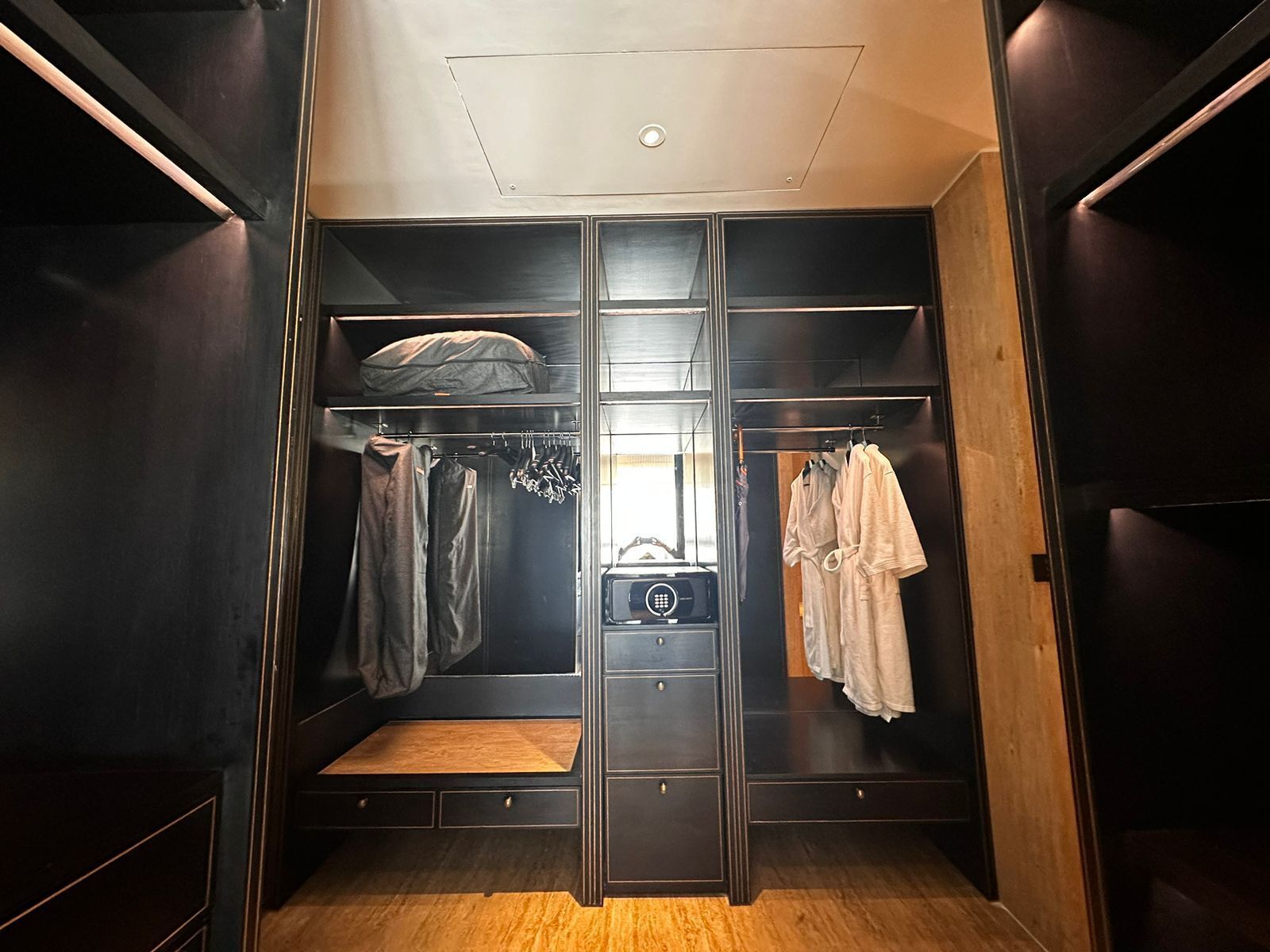 A walk-in closet with a mirrored wardrobe, a vanity with a radio, and a bench.