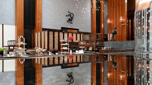 A modern hotel lobby with a reflective floor, wooden paneling, and a central seating area with tables and chairs. - Grand Hyatt Gurgaon (Gurugram)