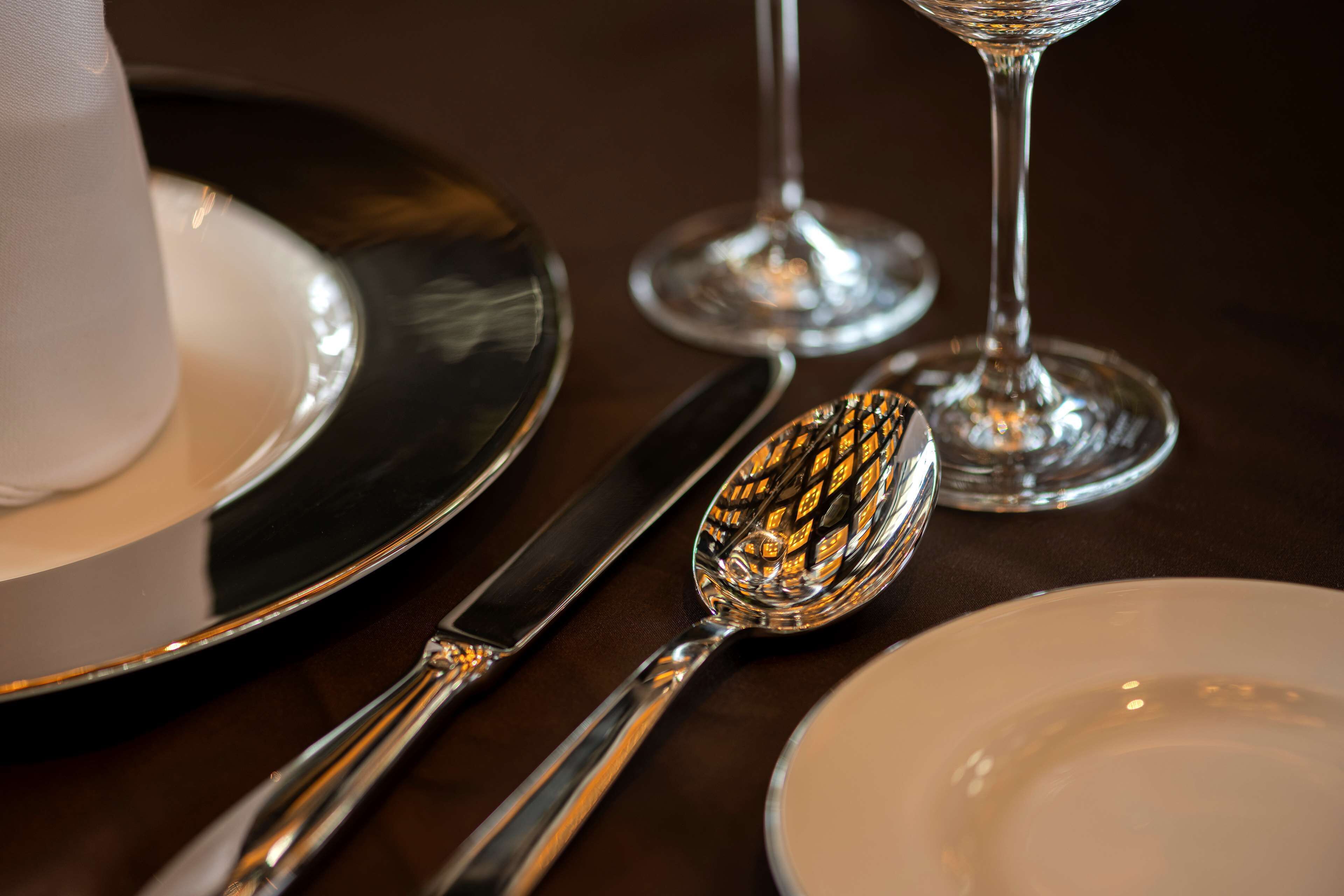 A dining table with a set of silverware, including a spoon, fork, and knife, and two wine glasses.