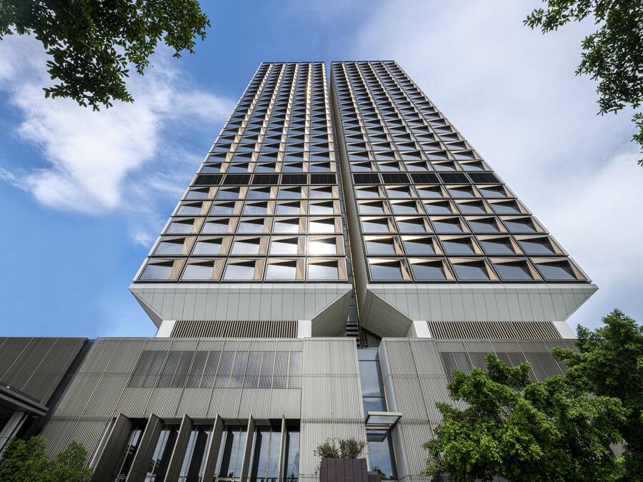 A modern high-rise building with a grid of windows and a central entrance.