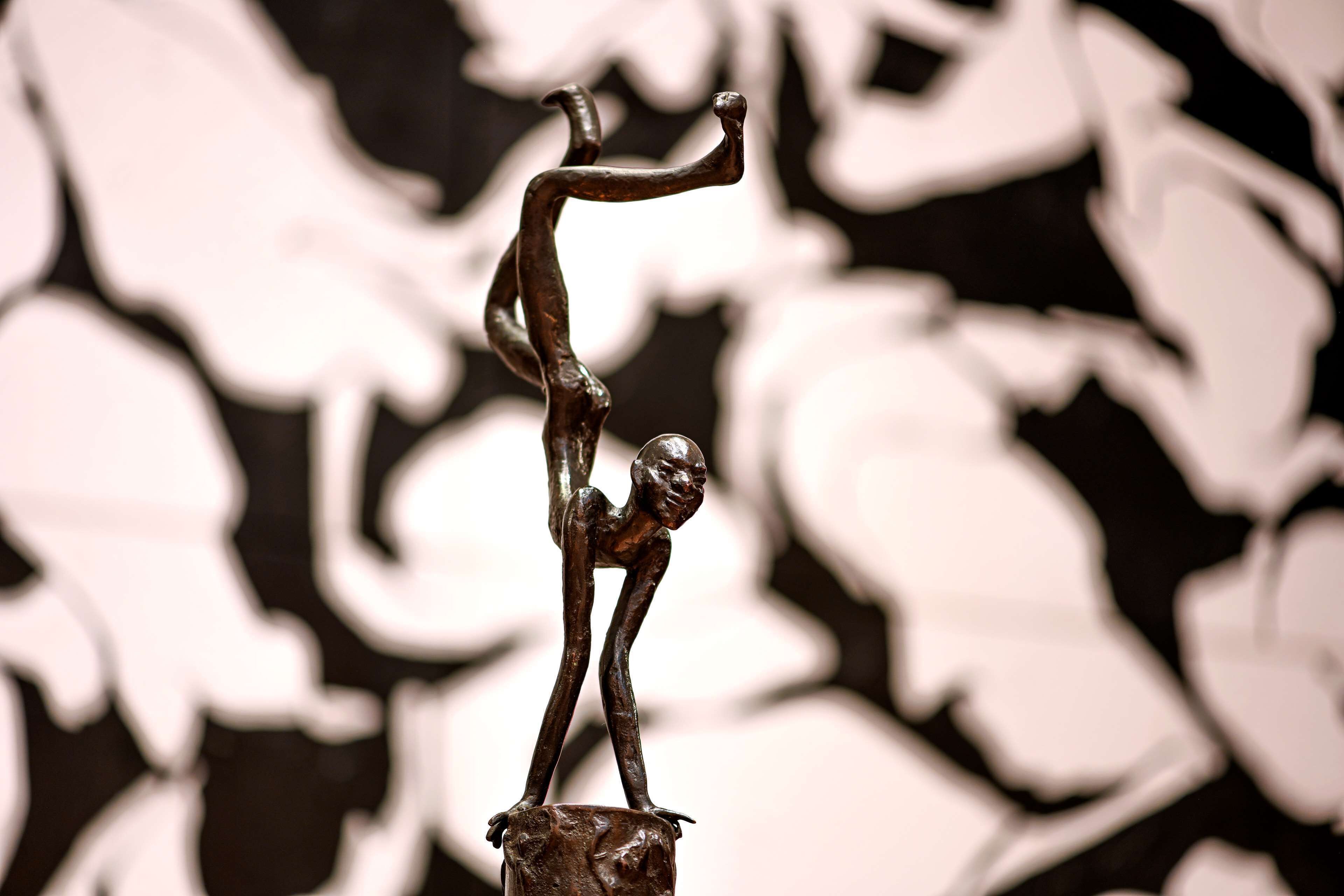 Una scultura raffigura una figura umana in equilibrio su una roccia.