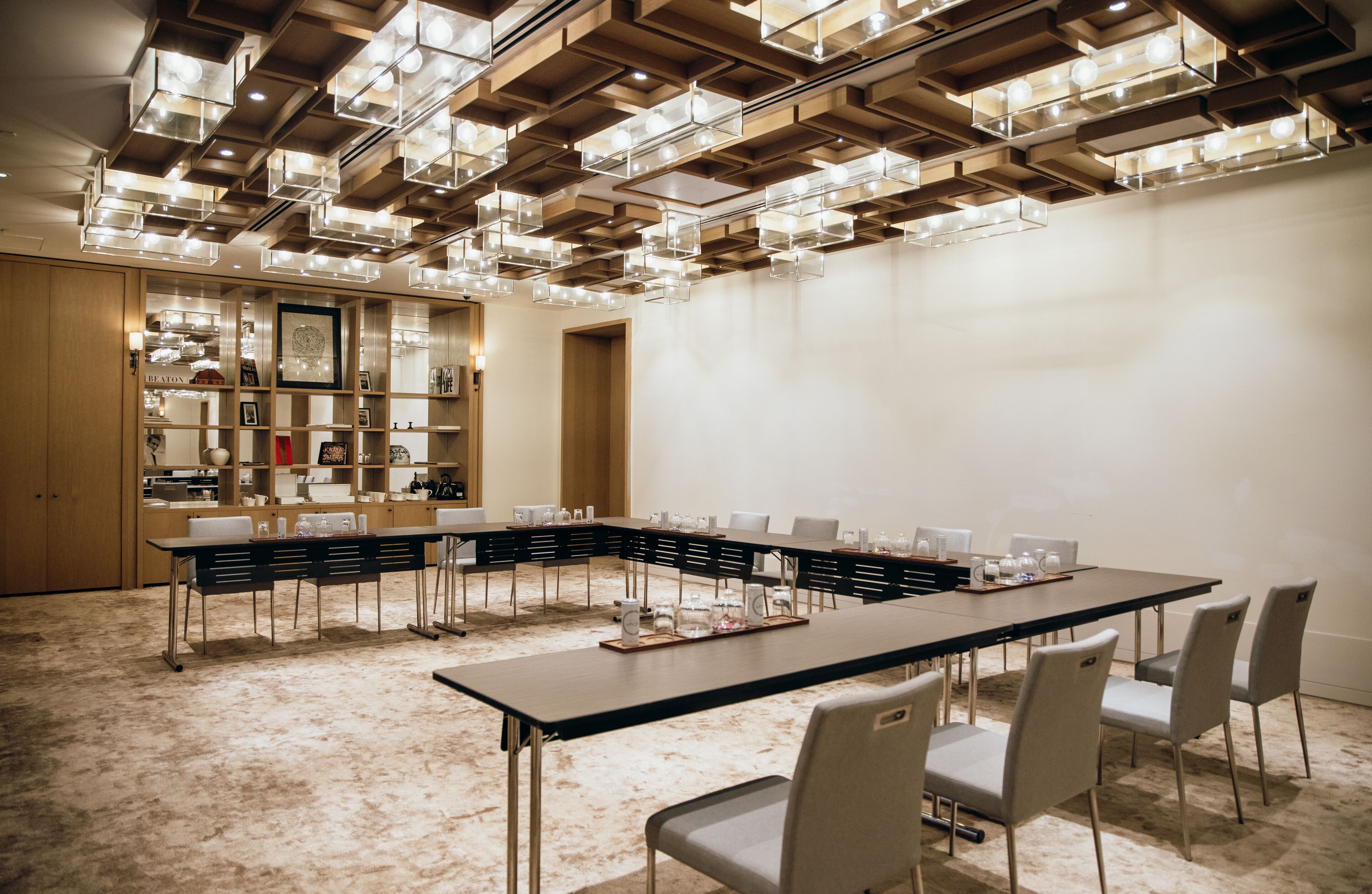 A conference room with a long table, chairs, and a ceiling with geometric light fixtures.