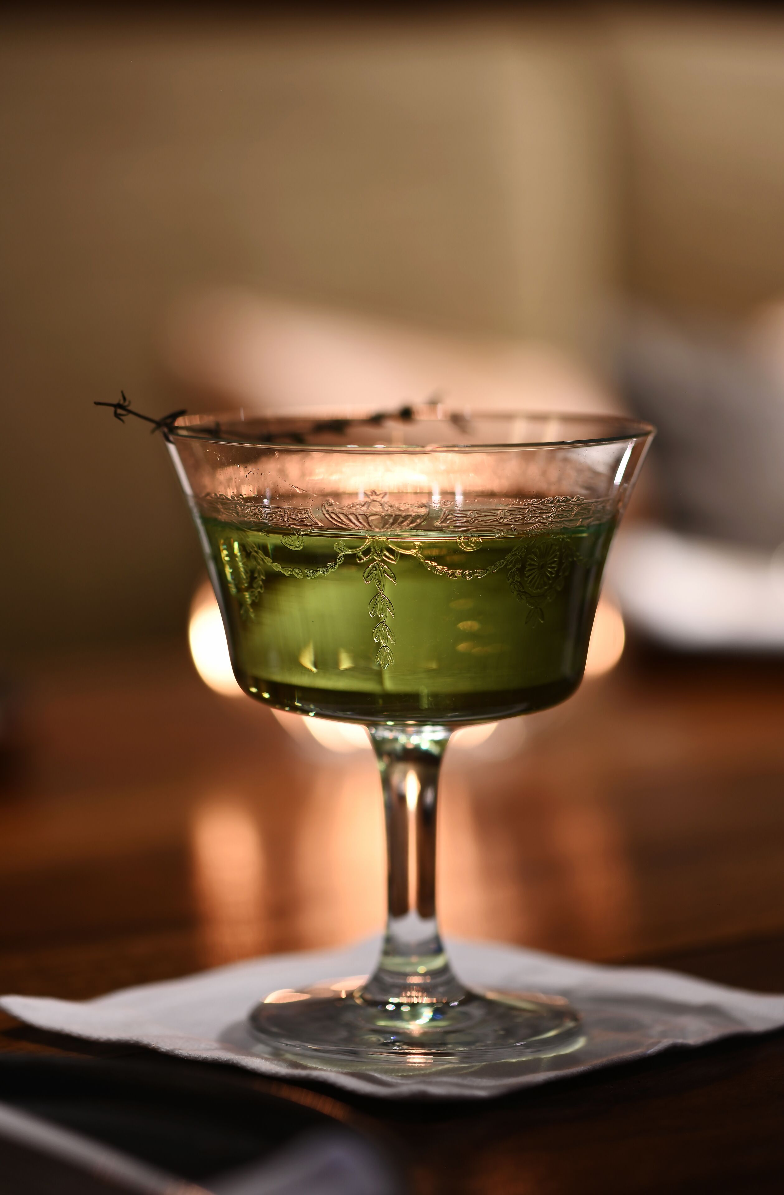 A glass of green liquid on a coaster.