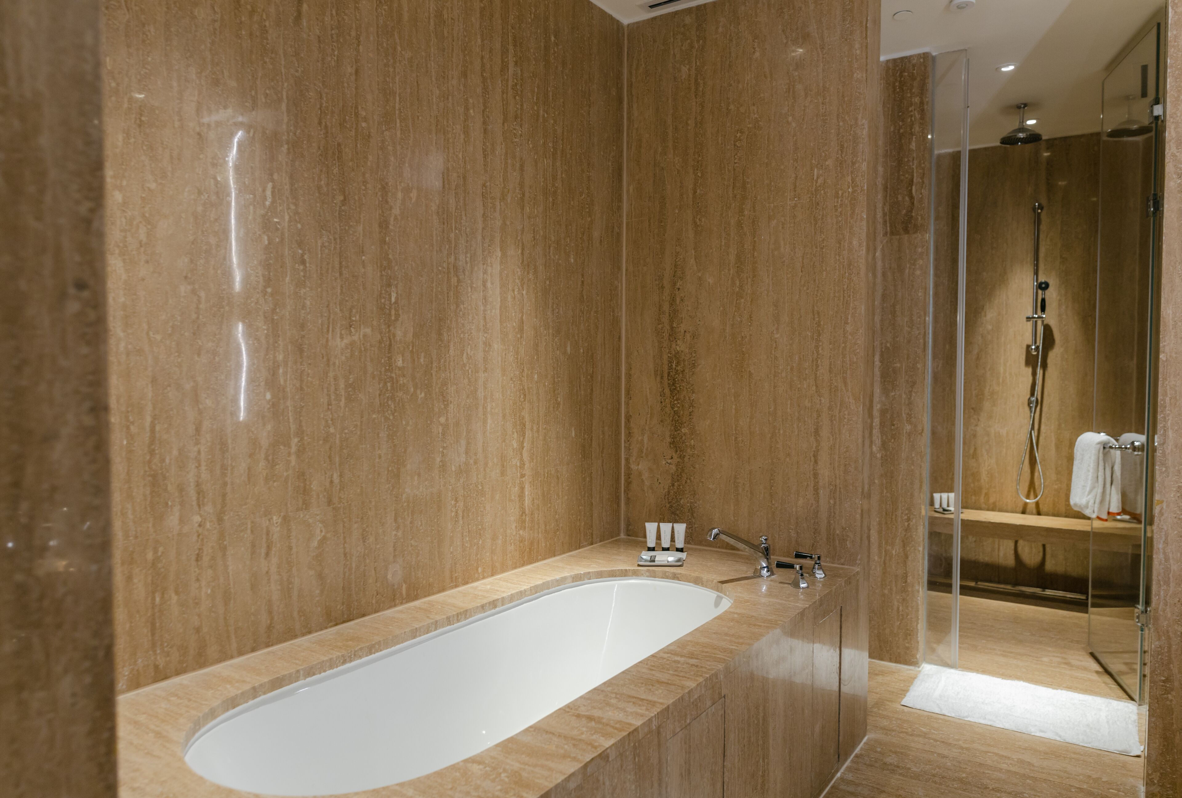 Un baño moderno con una bañera grande, una ducha con cerramiento de vidrio y un tocador de madera.