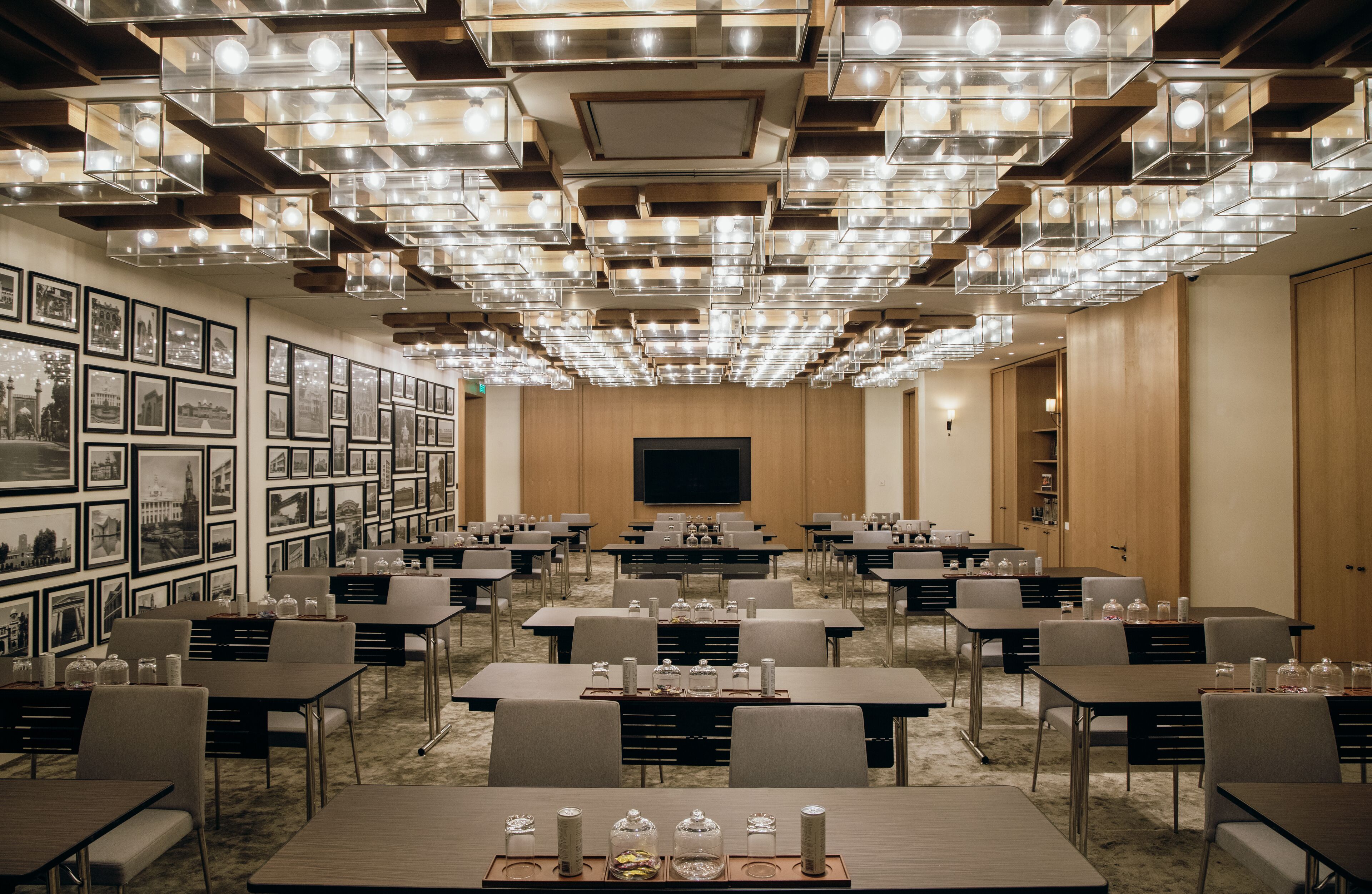Ein Konferenzraum mit Tischen, Stühlen, einer großen Leinwand und gerahmten Bildern an den Wänden.