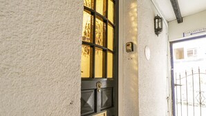 Paret blanca amb textura i una porta de fusta fosca, amb una manilla de bronze i un panell de vidre.