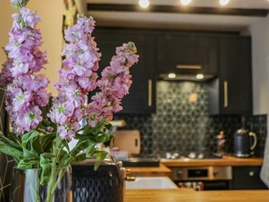 A modern kitchen with dark cabinets, a patterned backsplash, and a wooden countertop. - April Cottage (Whitby)