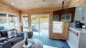 Ein gemütliches Blockhaus-Interieur mit einer Couch, einem Couchtisch und einer Küchenzeile mit einem großen Herd.