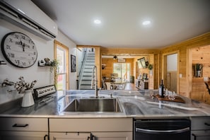 A kitchen with a large wall clock, a sink, and a wooden interior.