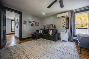 Ein modernes Schlafzimmer mit einer Eckcouch, einem großen Teppich und Wandbildern.