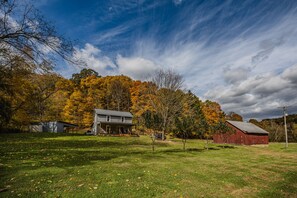 Ländliche Landschaft mit Haus, Scheune und blauem Himmel.