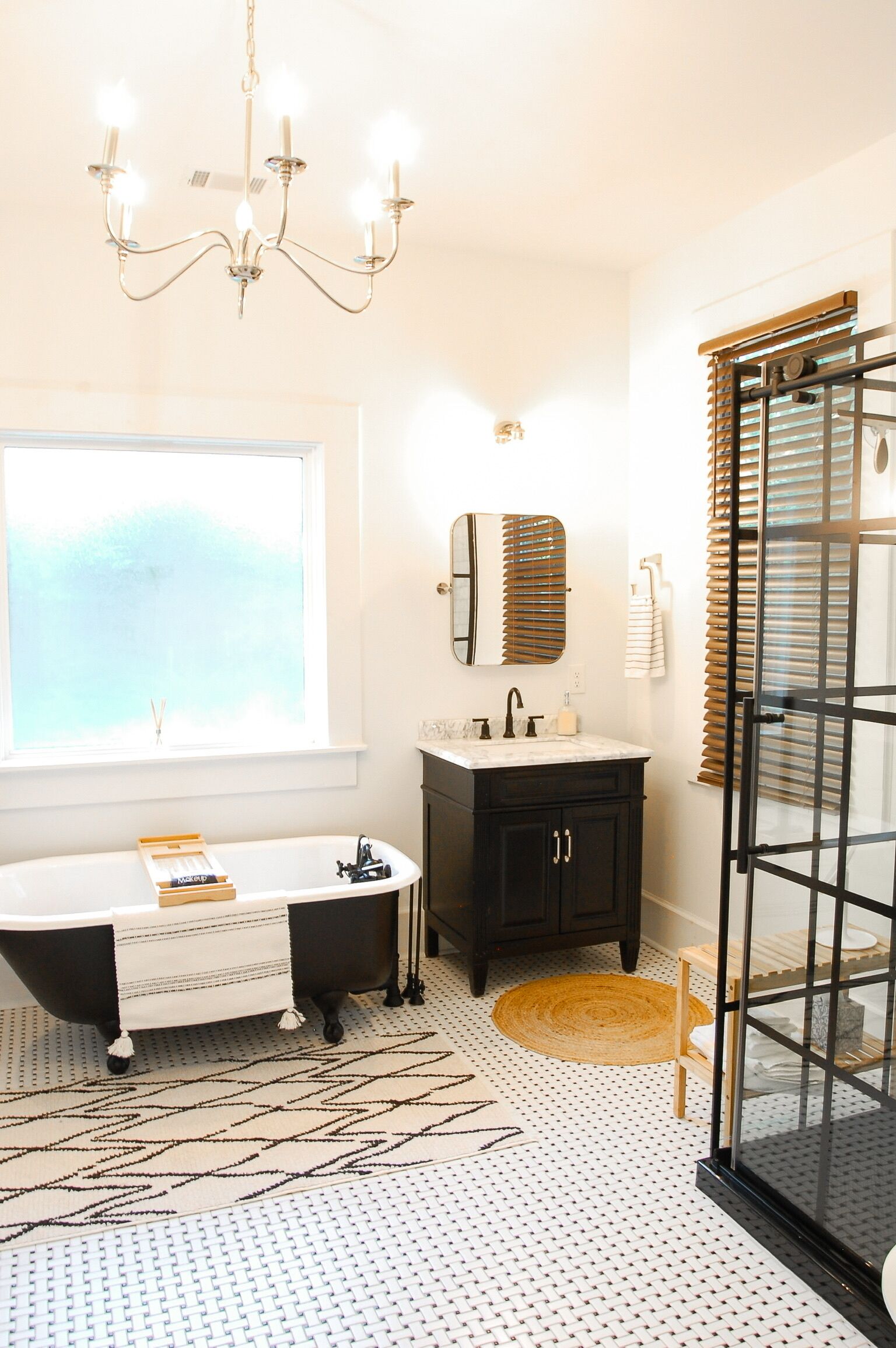 Une salle de bain moderne avec une baignoire sur pieds, un meuble-lavabo avec un miroir et une grande fenêtre.