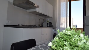 Una cocina compacta con armarios blancos, estufa integrada, microondas y lavadora.