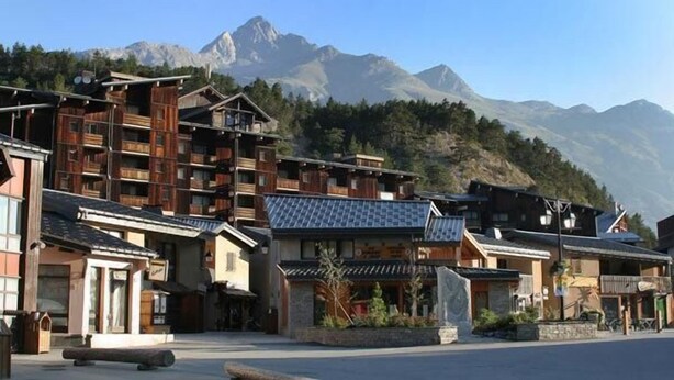 Un edificio de madera tradicional con varios balcones, frente a un paisaje montañoso.