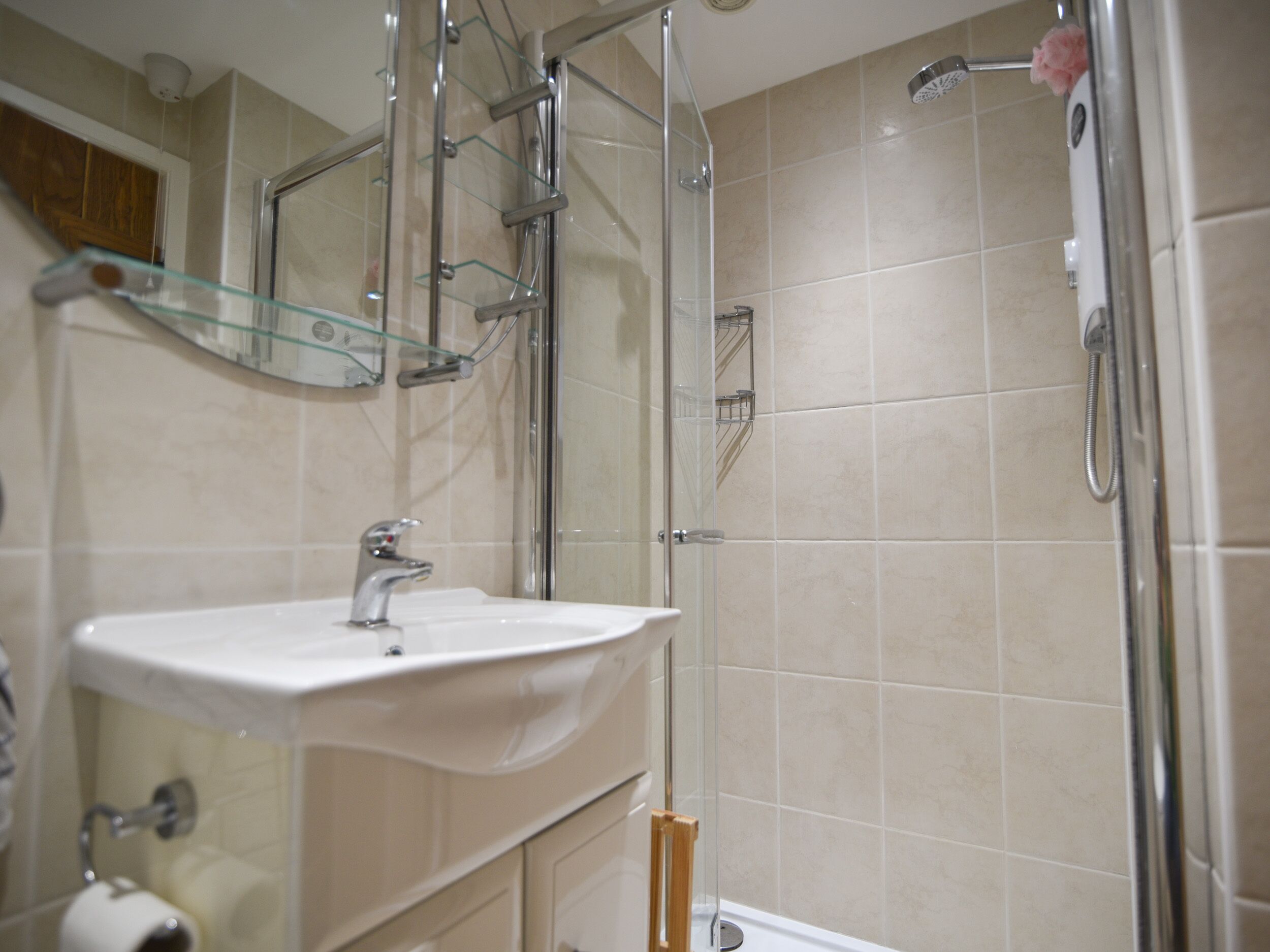 A bathroom with a glass shower enclosure, a sink with a mirror above it, and a toilet.