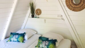 Un dormitori acollidor amb dos llits, un ventilador de sostre i decoració penjada a la paret.