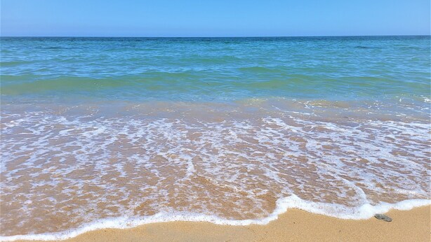 Una platja amb aigua cristal·lina i ones suaus.