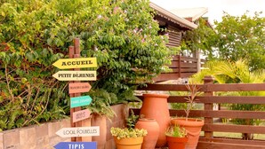 Un panneau indicateur indiquant la direction des différentes chambres d’hôtel et des commodités disponibles, notamment un jardin et les attractions locales.