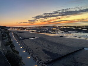 Un paysage côtier avec une promenade pavée longeant la plage, qui mène à une zone de plage.