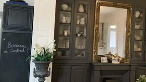 Un mueble de madera oscura con puertas de cristal que exhibe vajilla y un espejo grande y ornamentado.