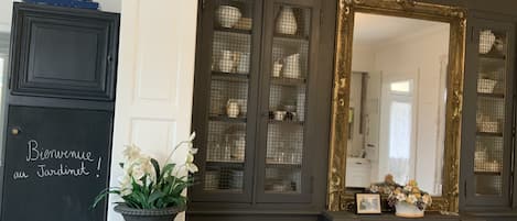 Un mueble de madera oscura con puertas de cristal que exhibe vajilla y un espejo grande y ornamentado.