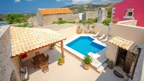 A rooftop pool area with a view of the sea, stone buildings, and a red wall. - Archontiko Galliaki in Crete (Rethymno)