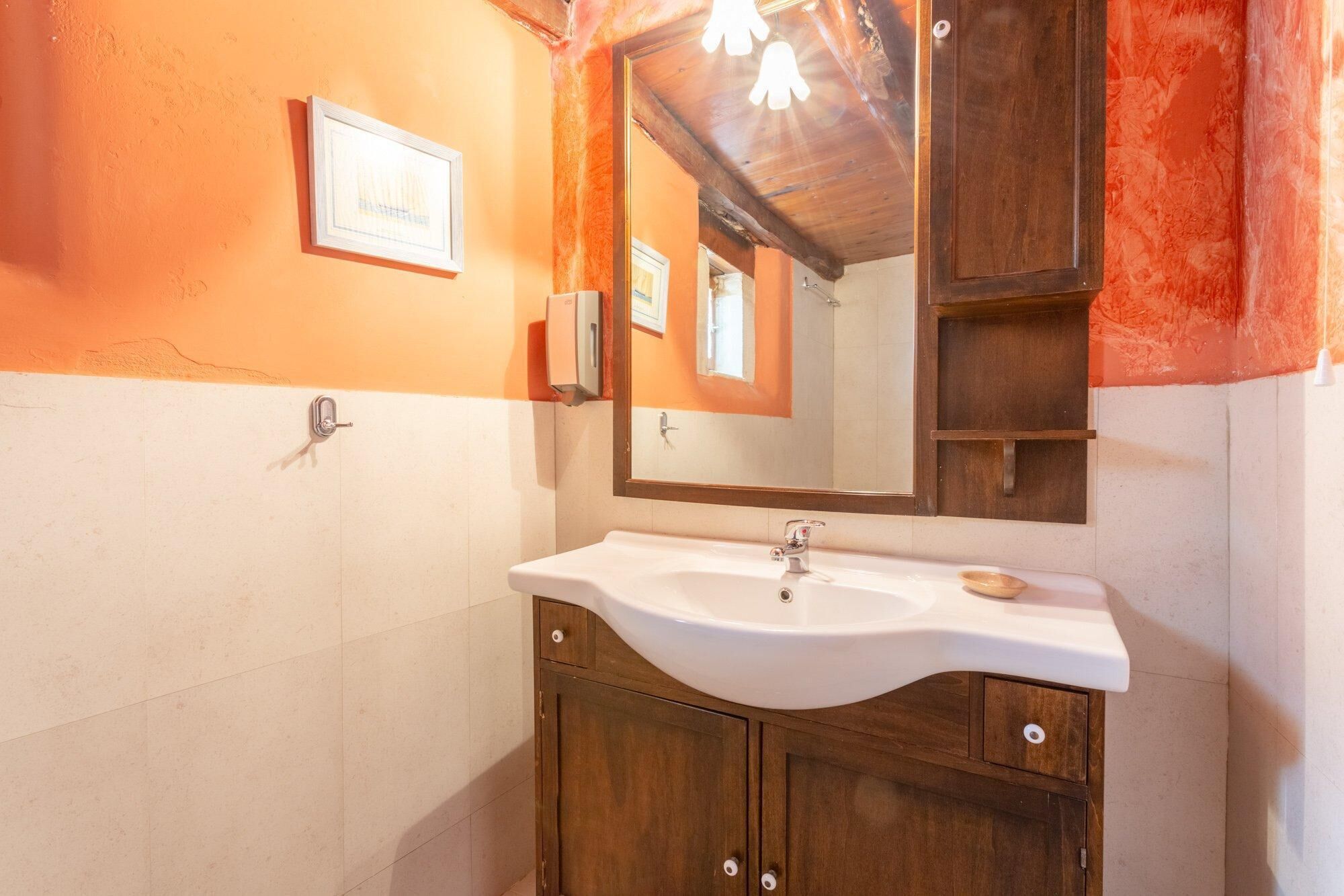 A bathroom with a white sink, wooden cabinets, a large mirror, and a wooden ceiling.