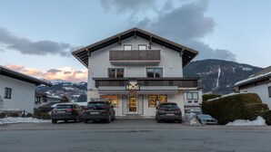 A two-story building with a sign reading "UHREN HAAS SCHMUCK". There are cars parked in front, and snow on the ground.