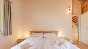 A bedroom with a wooden headboard, two bedside tables with lamps, and a neatly made bed with towels.