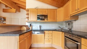 A kitchen with wooden cabinets, a black countertop, a stainless steel oven, and a microwave.