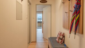 A hallway with a bench, a door, and a view of a balcony.
