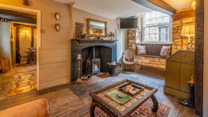 A cozy living room with a fireplace, stone walls, and a comfortable seating area. - Cotswold Cottage in Winchcombe Near Broadway (Cheltenham)