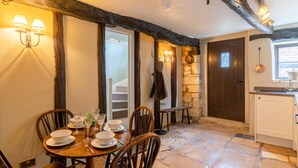 A dining area with a stone floor, wooden chairs, and a table set for four. - Cotswold Cottage in Winchcombe Near Broadway (Cheltenham)