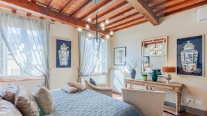 A bedroom with a bed, a chair, a vanity with a mirror, and artwork on the walls. - Casa Lucky a Modern Lucca Penthouse (Lucca)