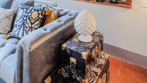 A cozy living room with a grey sofa, patterned cushions, a decorative white sphere, and a small table with a black and gold patterned table runner. - Casa Lucky a Modern Lucca Penthouse (Lucca)