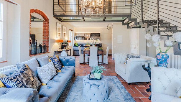 A spacious living room with a high ceiling, a staircase, and a kitchen in the background. - Casa Lucky a Modern Lucca Penthouse (Lucca)