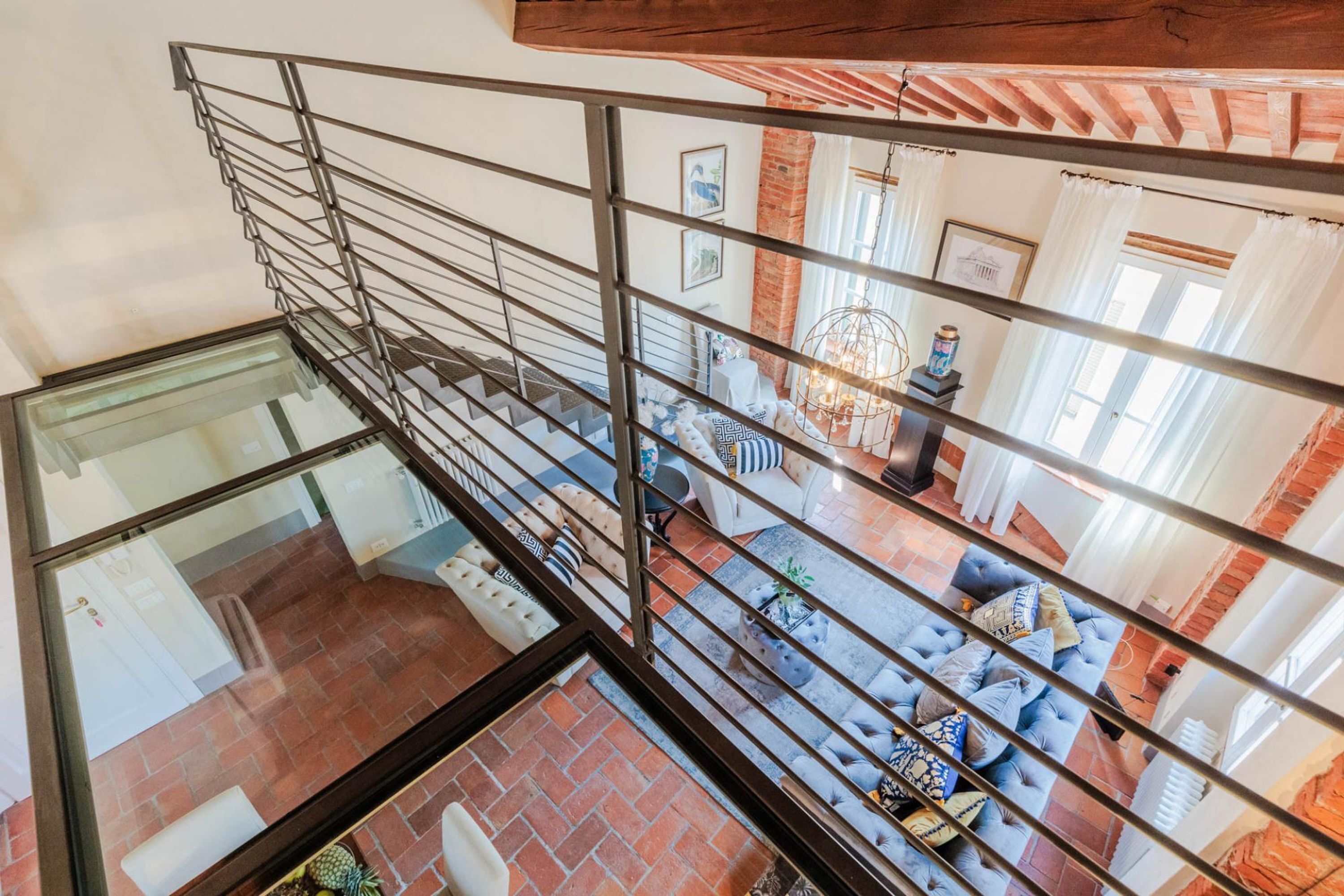A modern interior with a glass staircase, a cozy living area with a sofa set, and a dining table.