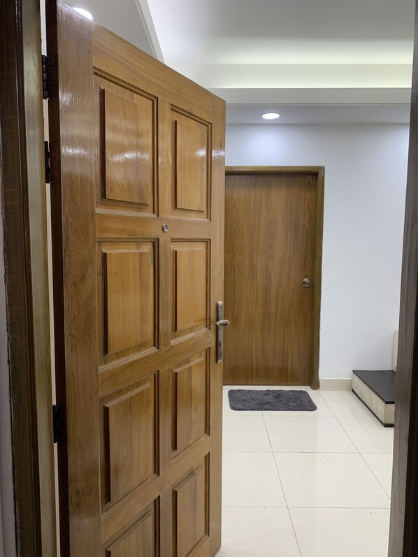 A wooden door with a metal handle, a dark rug on the floor, and a white tiled area.
