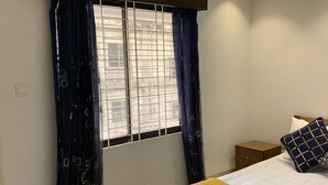 A bedroom with a bed, a nightstand, a window with curtains, and a ceiling light. - Captivating 2-bed Apartment in Dhaka (Dhaka)