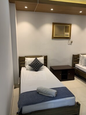A neatly arranged bedroom with a single bed, a bedside table, and a small bedside cabinet.